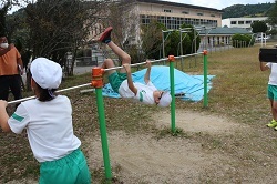 逆上がりをする様子を撮影する児童の写真