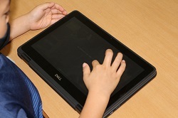 タブレットの画面にタッチして操作する児童の写真