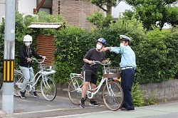 路上で自転車の乗り方の指導を受ける児童の写真