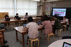 タブレット端末を操作しながら研修をうける教職員の写真1