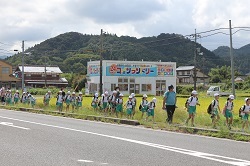 1列になって歩道を歩く児童の写真