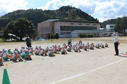 校庭で校長先生の話を聞く児童の写真