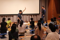 消防士の方のお手本を見る児童の写真