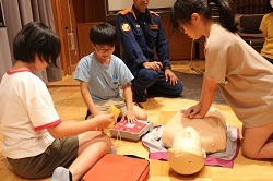 胸骨圧迫する児童とAEDを使用する児童の写真