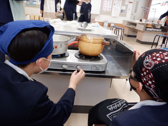 コンロの火加減を調節する児童