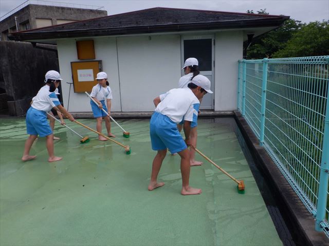 プールサイドを掃除する4年生