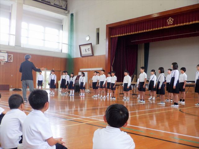 全校児童の前で、壮行演奏会で歌を発表する5年生