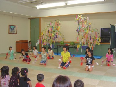 七夕飾りの前で銭太鼓をする小学生のようす