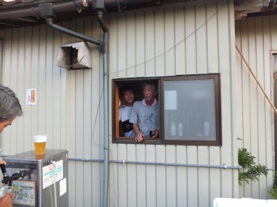 窓から顔を出す自治会長の生ビール販売のようす