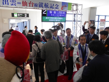 写真は、出雲縁結び空港「出雲ー仙台」線就航を記念し、仙台行きの乗客に記念品を配布している様子。