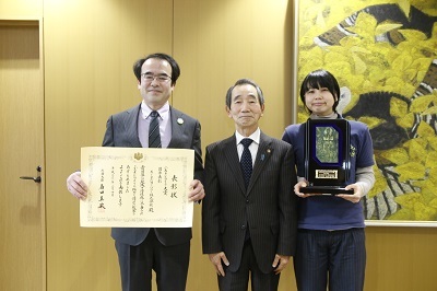表彰状と記念品を掲げる「えーひだカンパニー」代表者2人と近藤市長の写真
